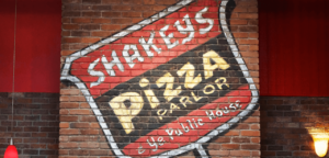 Shakeys Pizza logo on brick wall
